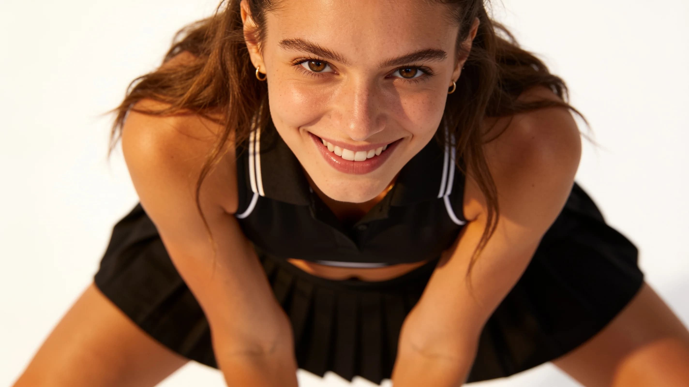 Wearing short black tennis skirt and a crop top shirt, portrait picture, looking at the viewer with a smile