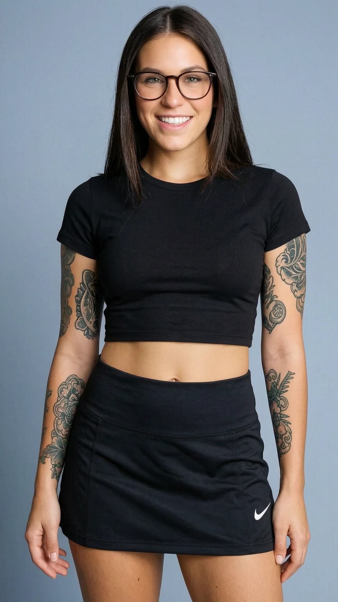 A 24-year-old Caucasian woman with straight brunette hair, green eyes, fit body type, wearing glasses and intricate tattoos, natural pubic hair, dressed in a short black tennis skirt and tight crop top shirt that exposes her midriff, captured in a close-up portrait from frontal eye-level angle with direct intense eye contact and a warm genuine smile, lips curved upward, confident standing pose with shoulders back, soft cinematic lighting highlighting skin texture and fabric details, realistic style, joyful mood. Flawless anatomy, no extra digits, no extra limbs, realistic skin texture, high-detail.