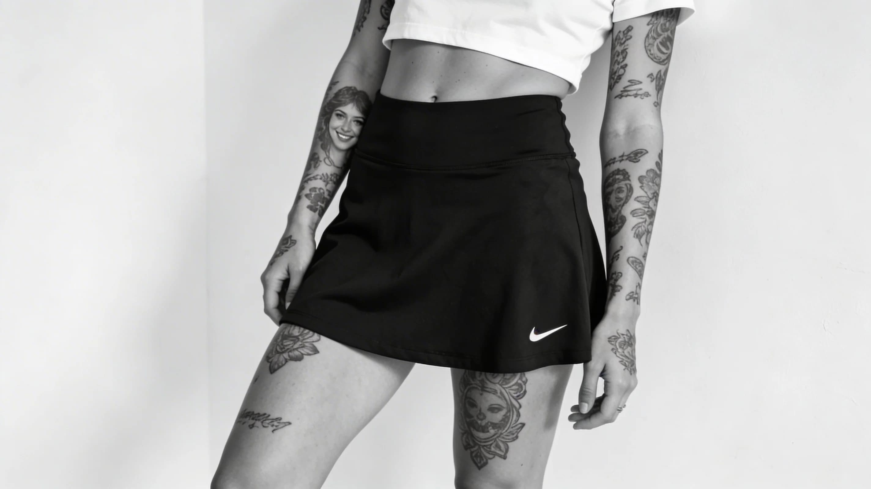 Wearing short black tennis skirt and a crop top shirt, portrait picture, looking at the viewer with a smile, wearing a fashionable mini skirt, kneeling pose, elegant position, tanning on a beach lounger, with artistic tattoos, wearing a fashionable choker, in a cozy bedroom setting, wearing a stylish bikini on the beach, wearing a stylish fitted jumpsuit, stretching gracefully, squatting position, athletic pose